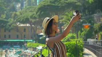 una mujer se toma selfies y usa videollamadas facetime en una ciudad turística de lujo en italia, europa.