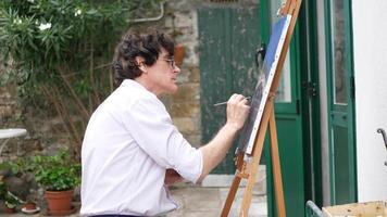 un artista dipinge un dipinto ad olio su tela all'esterno.
