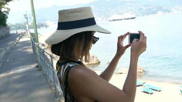 eine frau fotografiert mit ihrem handy in einem strandresort in einem luxuskurort in italien, europa.