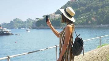 eine frau fotografiert mit ihrem handy in einem strandresort in einem luxuskurort in italien, europa.