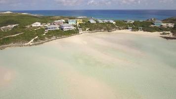 Vista aérea de drone de agua clara y casas en una playa y costa de una isla tropical en las bahamas, caribe.