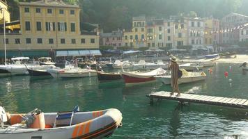 una mujer en un muelle en Portofino, Italia, una ciudad turística de lujo en Europa. video