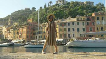 en kvinna som går med hatt och ryggsäckväska som reser i Portofino, Italien, en lyxig semesterort i Europa.