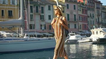 en kvinna som går med hatt och ryggsäckväska som reser i Portofino, Italien, en lyxig semesterort i Europa.