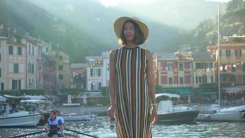 una donna che cammina con un cappello e una borsa zaino in viaggio a portofino, in italia, una località turistica di lusso in europa.