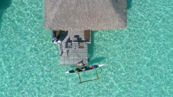 Aerial drone view of a man and woman couple in an overwater bungalow on Bora Bora tropical island. video