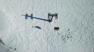 Aerial drone view of ski chair lifts and snow covered mountains in the winter.