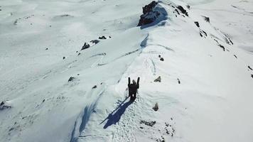 Aerial drone circling view of a skier with skis on top of a snow covered mountains in the winter.