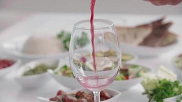 El vino tinto se vierte en un vaso en un hotel resort. video