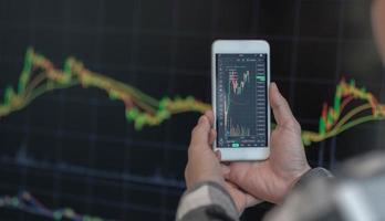 Business man trader investor analyst using mobile phone app analytics for cryptocurrency financial stock market analysis analyze graph trading data index investment growth chart on smartphone screen. photo