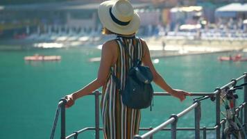 una mujer mira un club de playa del mar mediterráneo en una ciudad turística de lujo en italia, europa. video