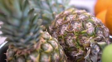 twee ananassen liggen in een bord in de keuken, slow-motion. mooie textuur van fruit video