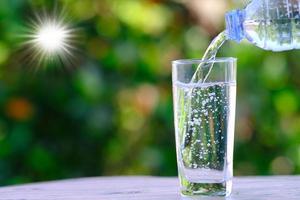 El agua fluye hacia un vaso sobre la mesa y el concepto de salud del agua mineral. foto