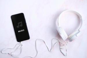 Smartphone con auriculares conectados sobre fondo blanco, escuchando conceptos musicales foto