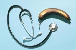 Minimal layout with a rotten banana and a traditional stethoscope with hard shadows photo
