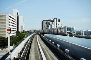 Grey train running through the Tokyo railing near the white building photo