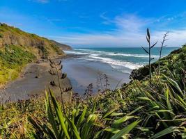 Las olas rompen en tierra en la playa muriwai, Auckland, Nueva Zelanda foto