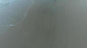 Toma aérea de niño jugando al fútbol en la playa al atardecer. video