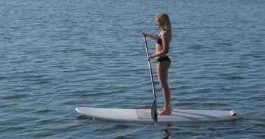 een jonge vrouw sup stand-up paddleboarding op een meer.