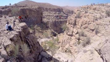 vue aérienne d'un homme en équilibre tout en marchant sur la corde raide et en slackline à travers un canyon.