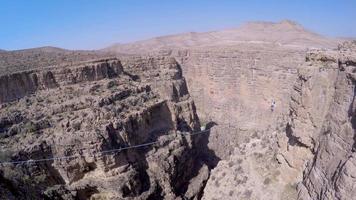 vue aérienne d'une femme en équilibre tout en marchant sur la corde raide et en slackline à travers un canyon. video