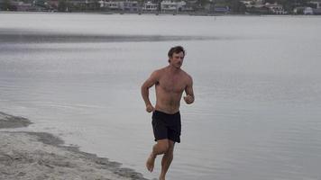 A man jogging on the bay and beach.