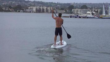 een man peddelt met zijn sup stand-up paddleboard in een meer.