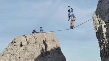 en man försöker balansera medan han slackar på en lina i bergen. video