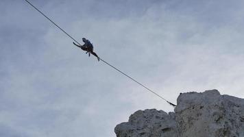 un homme essaie de s'équilibrer en slackline sur une corde raide dans les montagnes. video