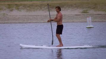 en man paddlar sitt sup stand-up paddleboard i en sjö.