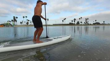volgweergave van een man die met zijn sup stand-up paddleboard in een meer peddelt.