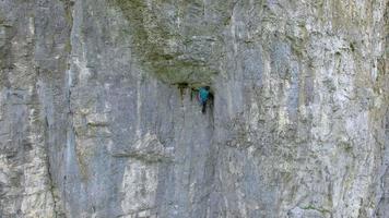 Aerial view of a man rock climbing up a mountain. video
