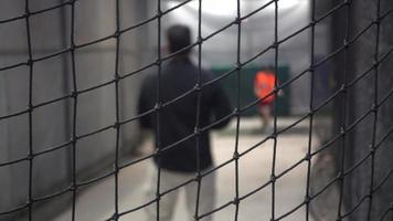 um treinador de beisebol joga nas gaiolas de batedura.