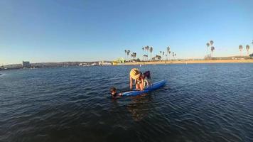 punto de vista de una mujer y un perro remando en una tabla de remo en un lago.