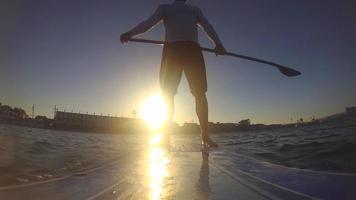 pov av en man som paddlar en sup stand-up paddleboard på en sjö vid solnedgången. video