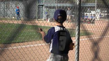 un niño en el banquillo en un juego de béisbol de la liga pequeña. video