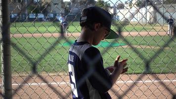 un niño en el banquillo en un juego de béisbol de la liga pequeña. video