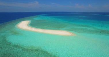 Vista aérea de un hombre y una mujer desayunando en la playa de un banco de arena de una isla tropical. video