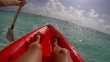 pov vista de una pareja de hombre y mujer en kayak alrededor de una isla tropical.