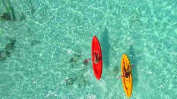 Aerial drone view of a man and woman couple kayaking around a tropical island. video