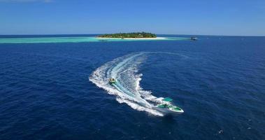 vista aérea do drone de um homem e uma mulher em um tubo inflável rebocando atrás de um barco para uma ilha tropical. video