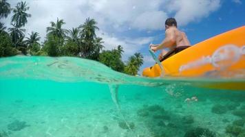 chupito de agua de un hombre en kayak alrededor de una isla tropical.