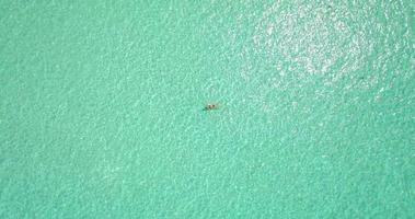 Luftdrohnenansicht einer Frau, die auf einer tropischen Insel schwimmt und schwimmt.