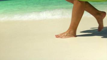 una mujer vestida con un pareo camina por la playa en un hotel resort en una isla tropical. video
