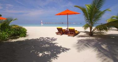 vista aérea de drone de sillas de playa vacías y sombrillas en una isla tropical en las maldivas.