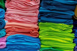 Cerca de coloridas camisetas apiladas en estantes foto