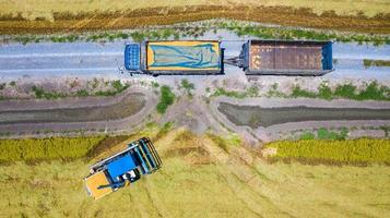 Vista aérea superior de la máquina cosechadora y el camión que trabaja en el campo de arroz, vista desde arriba foto