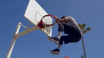 un hombre hace un slam dunk mientras juega baloncesto uno contra uno en una cancha de playa. video