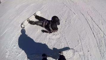 una mujer que practica snowboard se cae y se estrella mientras practica snowboard cuesta abajo en una estación de esquí. video
