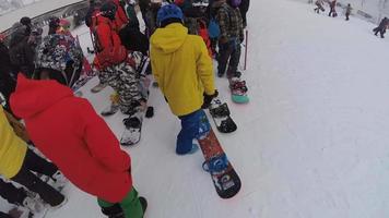 POV of a snowboarders and skiers standing in a lift line at a ski resort. video